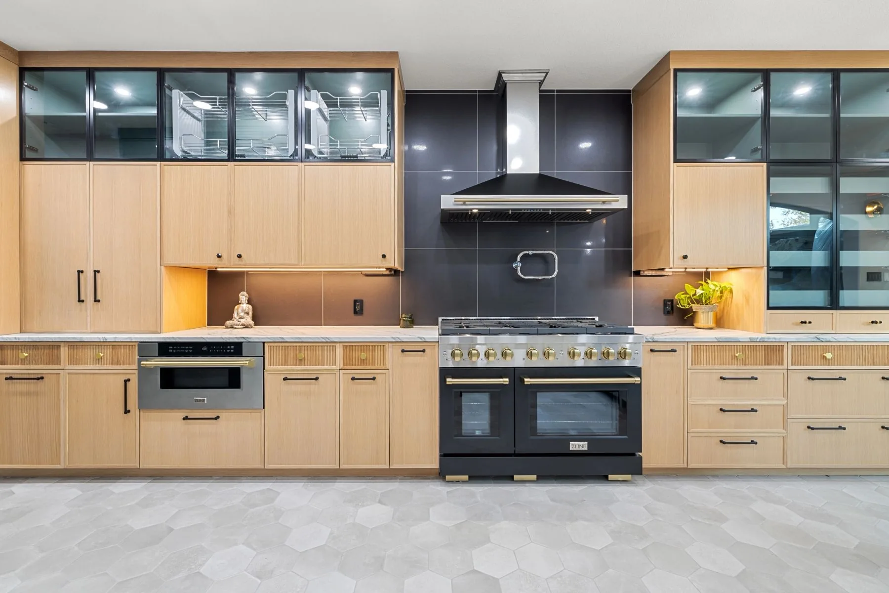 Custom white oak kitchen by Westcreek with glass display cabinets, black range, and brass hardware