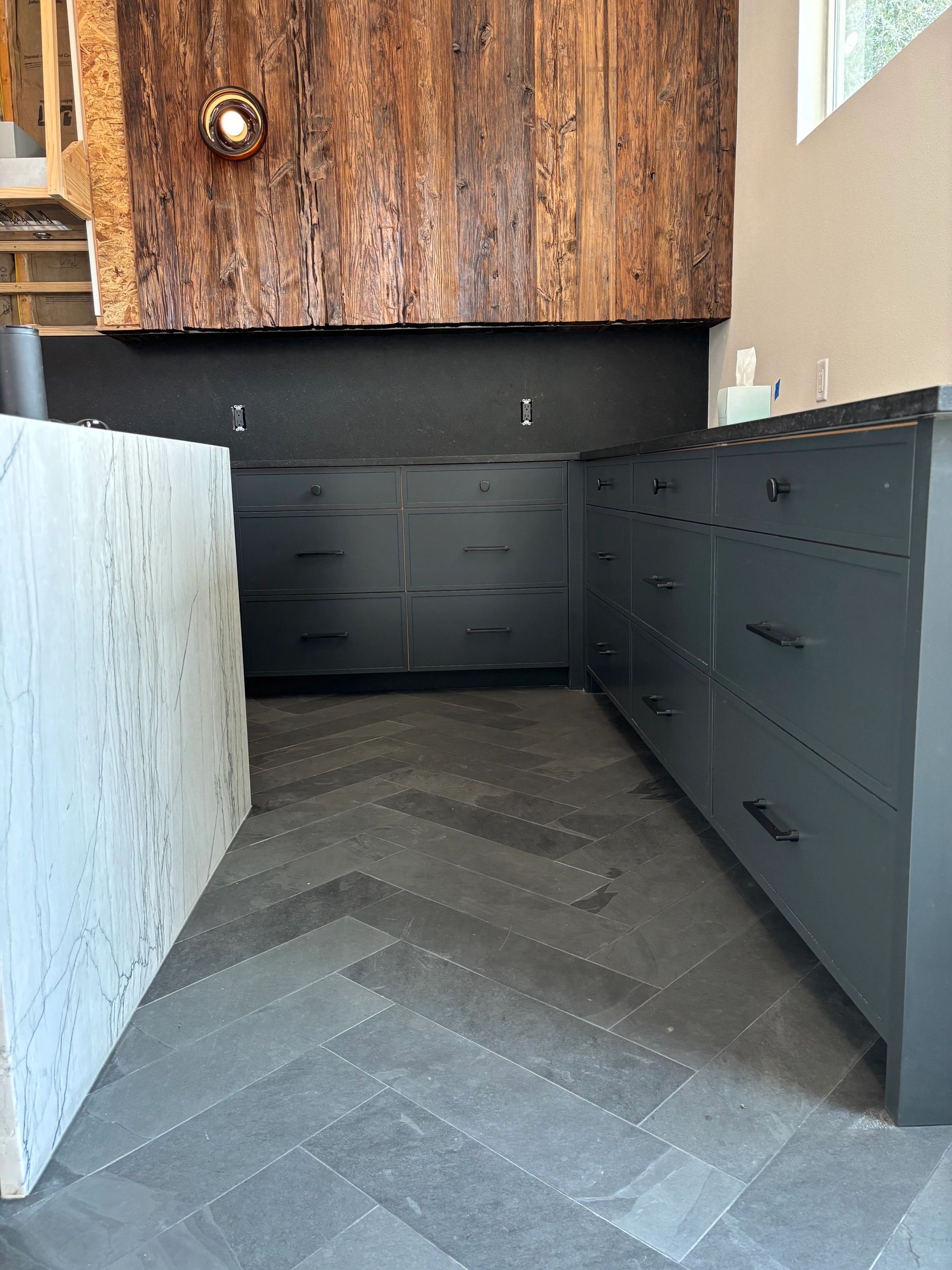 Charcoal kitchen cabinets with black hardware and a reclaimed wood vent hood by Westcreek