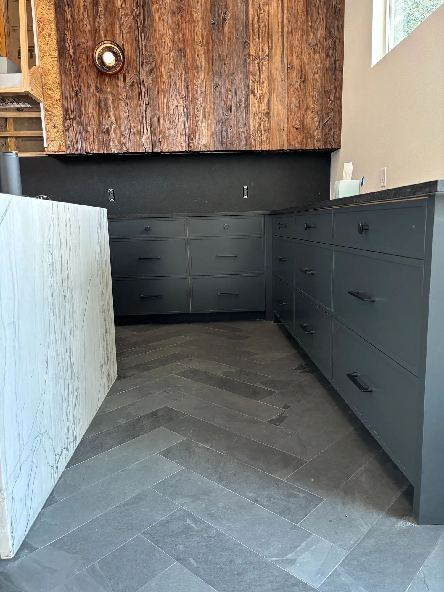 Charcoal kitchen cabinets with black hardware and a reclaimed wood vent hood by Westcreek