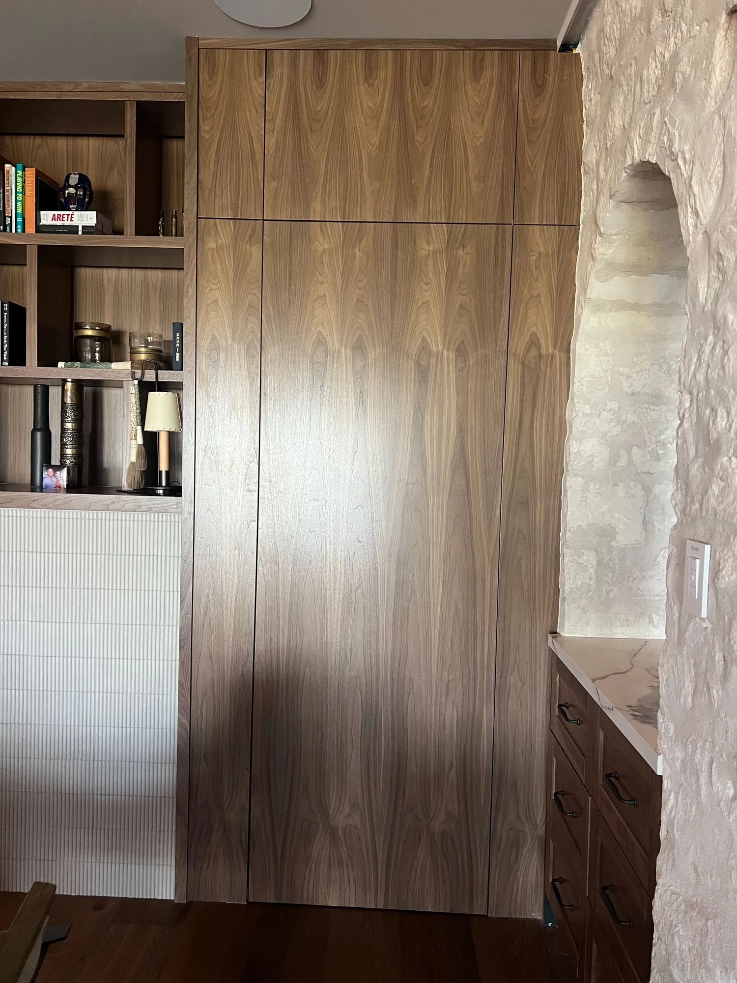 Walnut pantry built-in beside a limestone wall by Westcreek
